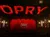 The image shows the interior of the Grand Ole Opry with red curtains on stage, large illuminated