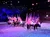 A group of riders on horseback carry the United States flag in an indoor equestrian show, creating a vibrant and patriotic display.