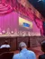 An audience is seated in a theater with ornate decorations and a screen displaying promotional content for streaming services.