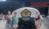 Three people are posing in front of a large Titanic sign and monument under a clear sky.
