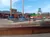 A person in lumberjack attire is walking on floating logs in a water pool at an outdoor lumberjack show.