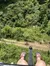 The image shows a person's feet dangling high above a lush green landscape, suggesting they are on a ride or seated at a considerable height.