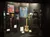 The image is of a display case showcasing various music-related artifacts and apparel, including a guitar and stage costumes, accompanied by informational placards.