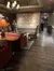 The image shows an interior space with rich wooden floors, a mural of musicians on the wall, and a person standing near a sitting area with upholstered furniture and table lamps.