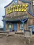 The image shows a rustic wooden building with a large sign that reads