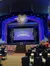 The image shows the interior of a theater with a stage set for a performance titled