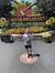 A child is standing in front of the Silver Dollar City sign, adorned with giant sunflowers and an ax, during the Ozark Mountain Summer Celebration.