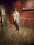 A lifelike figure dressed in traditional Western attire stands next to a