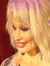 A wax figure of a famed female performer with a microphone stands before a red curtain backdrop, giving the impression of being ready to sing.