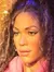 A wax figure of a woman posing confidently against a shimmering, multicolored curtain backdrop, accessorized with sparkling footwear and casual clothing, suggests a blend of glamour and casual style.