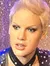 Two wax figures resembling celebrities are positioned in front of a glittery backdrop that gives the impression of a glamorous stage setting.