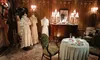 The image shows a classically decorated room with vintage dresses on mannequins, antique furniture, and an elegantly set small dining table, creating a historical ambiance.
