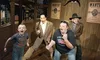 The image shows a lively scene with two real people and two wax figures, all with excited expressions, set against a Wild West backdrop with