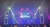 The image shows an audience waiting in front of a concert stage that is set up with lighting, a large screen displaying what appears to be a social media handle, and letter 
