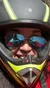 A person in a red hoodie is smiling for a selfie while wearing a black and yellow motorcycle helmet and sunglasses.