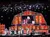 Musicians perform onstage at the Grand Ole Opry beneath illuminated stage lighting.
