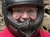 Two people are wearing helmets and sitting on all-terrain vehicles (ATVs) on a dirt trail surrounded by forest.