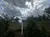 This image shows a chairlift on a hill with lush vegetation, under a dramatic sky with sun rays piercing through the clouds.