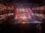 A theatrical performance is taking place on a vibrant stage in front of an attentive audience in a multi-tiered theater.