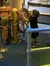 A young child is reaching up to turn a large ship's steering wheel at an indoor exhibit.