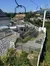 The image captures a scenic chairlift station with people, surrounded by greenery on a sunny day.