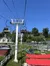A ski-lift style chairlift ascends a hill with a clear blue sky in the background, passing over a summer toboggan track.