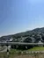 The image shows a clear day overlooking a sprawling town with buildings, roads, and trees framed by a blue sky.