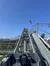A mountain coaster cart ascends the track with an American flag fluttering in the background against a clear blue sky.