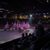 The image shows a procession of horse riders carrying American flags in an indoor arena while an audience watches from dining tables.