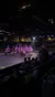 The image shows a procession of horse riders carrying American flags in an indoor arena while an audience watches from dining tables.