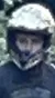 Three individuals on ATVs are paused on a gravel path with a lush green forest in the background.