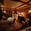 This image shows a dimly lit, ornately decorated room with period furniture and mannequins dressed in vintage clothing, suggesting a historical exhibit or museum setting.