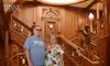 A man and woman are posing for a photo on a grand staircase that is a replica of the Titanic's, indicating they might be at a Titanic museum attraction.