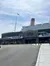 The image shows a large, Titanic-themed exhibit or attraction with the iconic funnel and the American flag flying above it, as visitors walk around the entrance area.