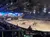 A lively equestrian show with performers in costumes and a themed arena is being watched by an audience seated around the perimeter.
