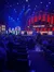 A group of musicians is performing on the stage of the Grand Ole Opry in front of a seated audience.