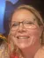 A person is posing for a selfie with a lifelike wax figure wearing round pink glasses.