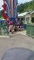 A group of people is seated on a star-spangled amusement park ride, with some participants looking excited and an attendant helping to secure a rider.