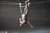 A person is performing an aerial stunt, hanging upside down by their feet from a wire high above the ground.