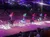 Riders on horseback proudly display colorful flags in an arena before an audience.
