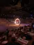 Audience members are watching a dramatic performance involving a ring of fire in an indoor arena during a dining experience.