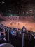 Audience members enjoy a live performance featuring horses and riders in an arena setting.