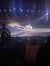A person on horseback performs in an illuminated arena before an audience.