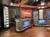 The image shows a modern and well-lit radio broadcast studio with multiple screens, a desk for the host, and decorative elements featuring the studio's logo.