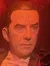 A person is playfully imitating a vampire bite on a wax figure dressed as the classic interpretation of Dracula, in a dimly lit, Gothic-themed room.