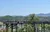 Visitors are enjoying the view from an elevated wooden viewing platform against a backdrop of rolling hills and a clear blue sky.