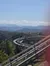A mountain coaster with complex, twisting tracks set against a backdrop of scenic hills under a clear sky.