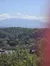 The image shows a scenic view of a small town nestled among lush greenery with a backdrop of majestic mountains under a clear sky.