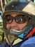 A person in a helmet and goggles is sitting on an ATV in a forested area.
