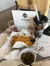 The image shows a meal with cheese-covered nachos, a side of jalapeños, sour cream, a drink with a camo-patterned cup, and a clear cup of a brown liquid, set on a marble table with a menu stand from Skyland Ranch in the background.